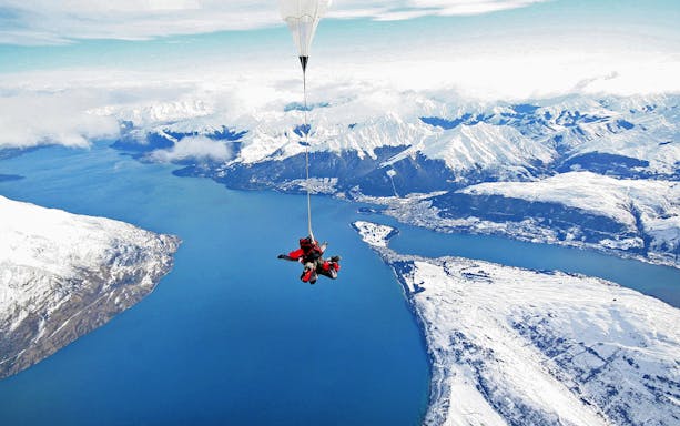 Tandem skydive over Lake Wakatipu with snow-capped mountains in Queenstown, New Zealand.