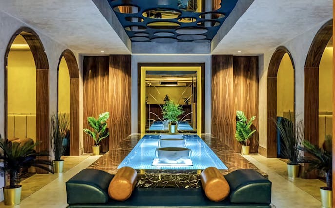 Private Turkish Bath interior with central pool, arched doorways, and decorative plants.