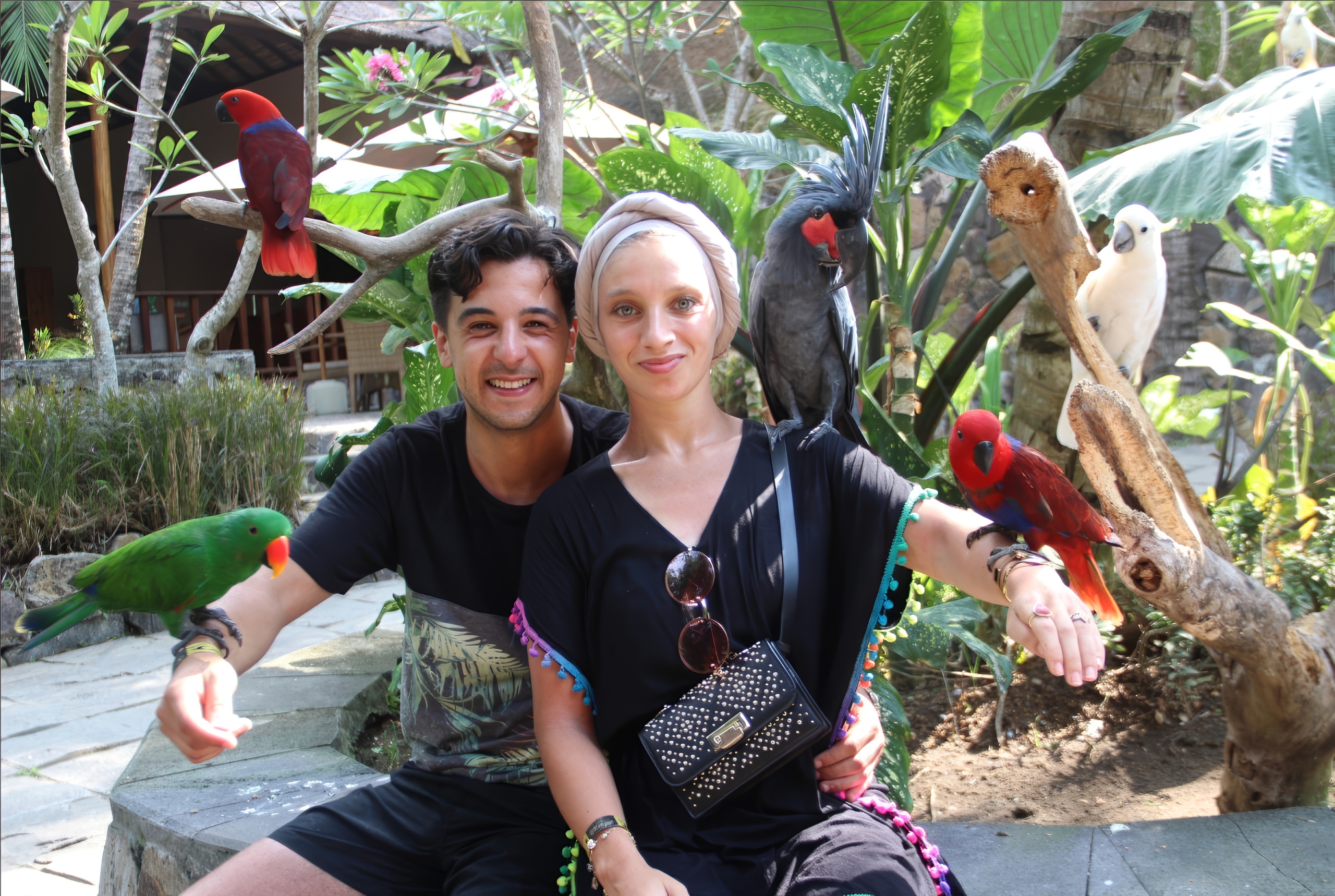 Couple with colorful birds at Lombok Wildlife Park, Indonesia.