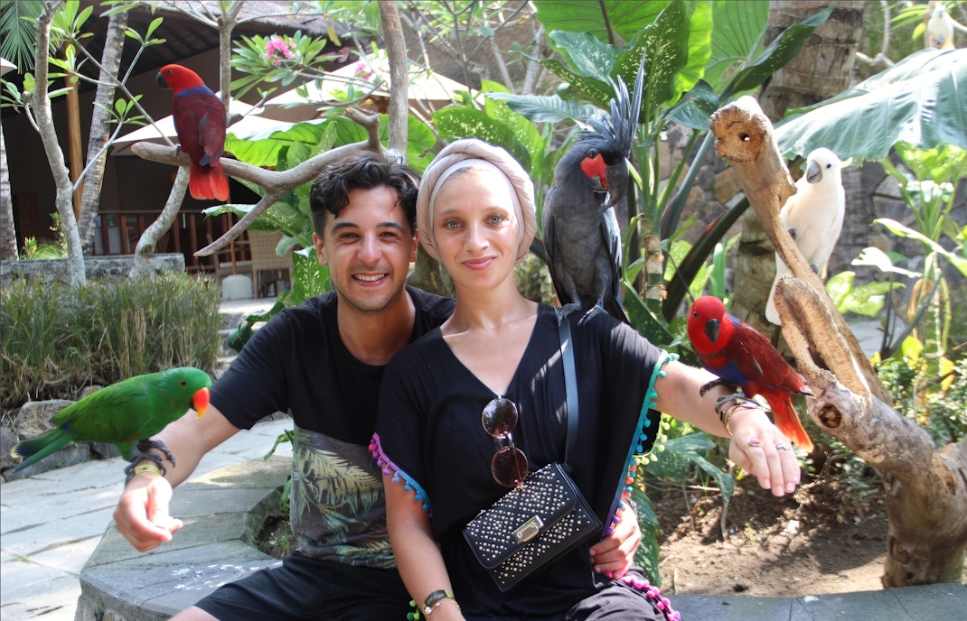 Couple with colorful birds at Lombok Wildlife Park, Indonesia.