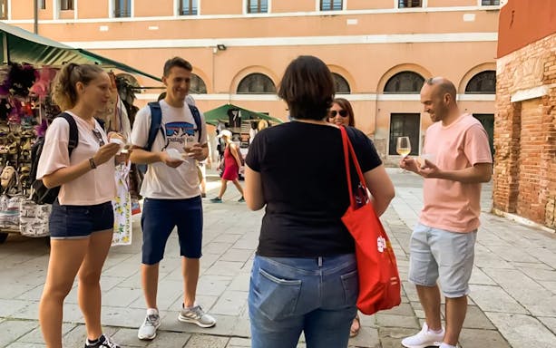 Tourists enjoying a guided street food tour at Rialto Market, Venice.