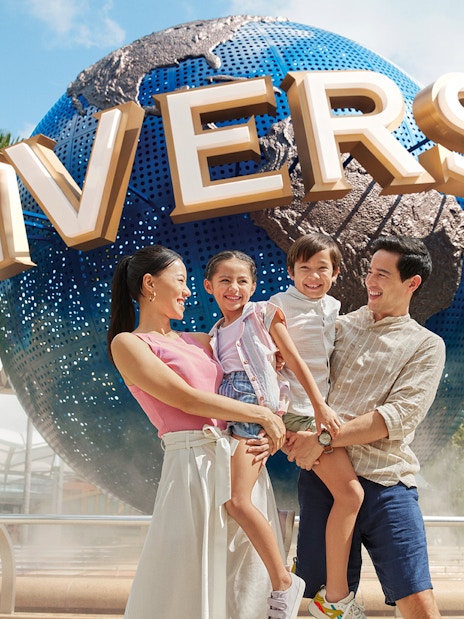 Family smiling in front of Universal Studios Singapore globe.