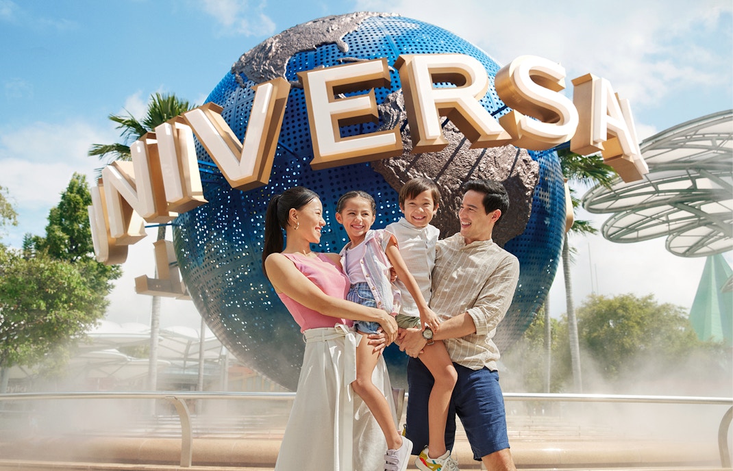 Family smiling in front of Universal Studios Singapore globe.
