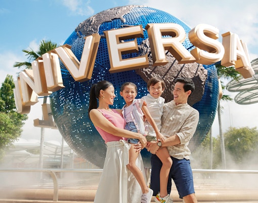 Family smiling in front of Universal Studios Singapore globe.