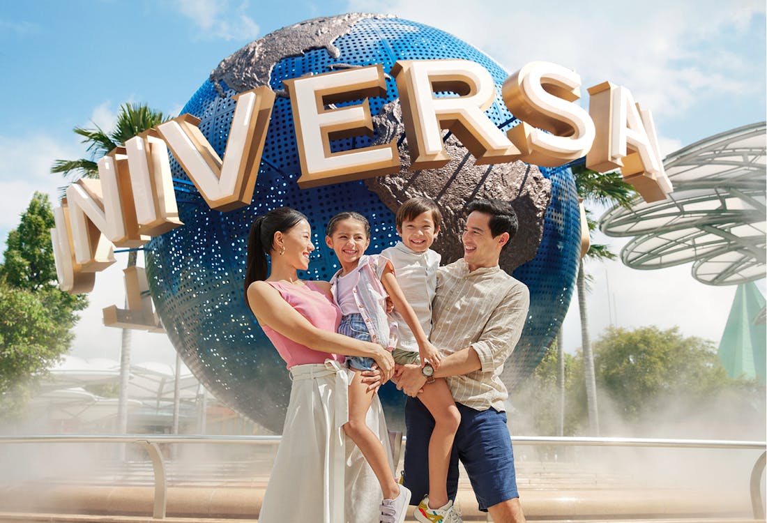 Family posing in front of Universal Studios Singapore globe entrance.