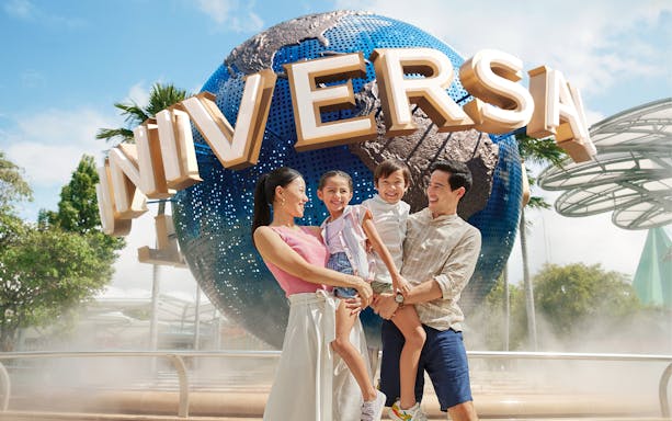 Family smiling in front of Universal Studios Singapore globe.