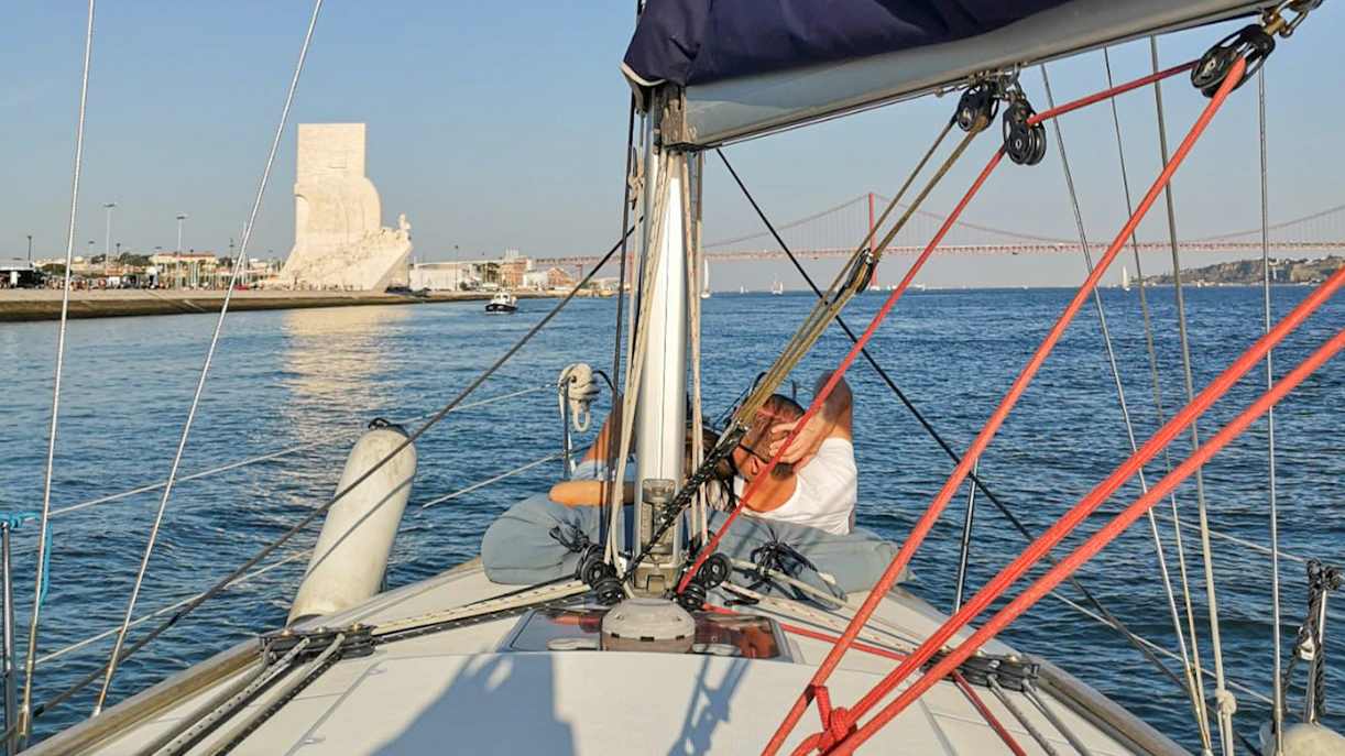 Tourist on Lisbon cruise boat viewing Monument of Discoveries and 25 de Abril Bridge.