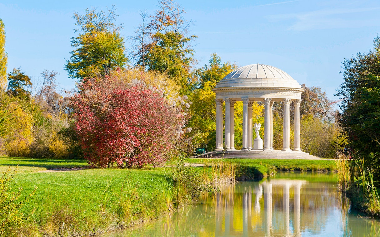 Temple of Love in Trianon gardens, surrounded by trees and reflected in a pond.
