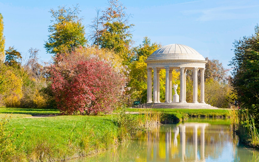 Temple of Love in Trianon gardens, surrounded by trees and reflected in a pond.