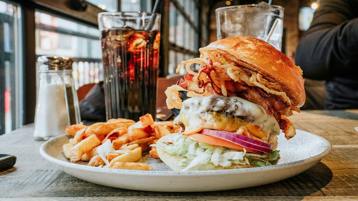 Burger served on a plate with a view of Niagara Falls, Canada in the background.