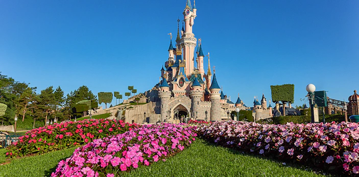 Sleeping Beauty Castle at Disneyland Paris with vibrant flower beds in the foreground.
