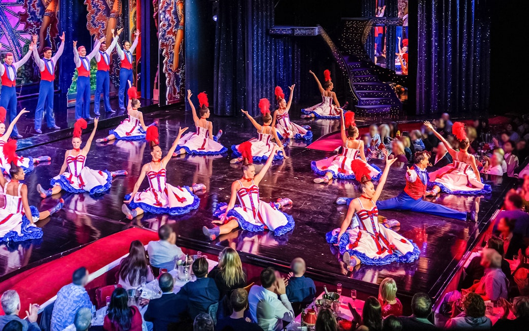 Dancers performing at Moulin Rouge show in Paris with audience dining.