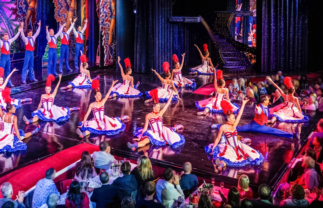 Dancers performing at Moulin Rouge show in Paris with audience dining.