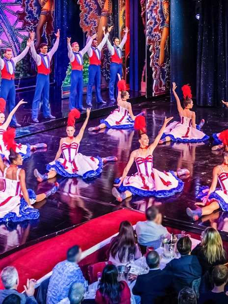 Dancers performing at Moulin Rouge show in Paris with audience dining.