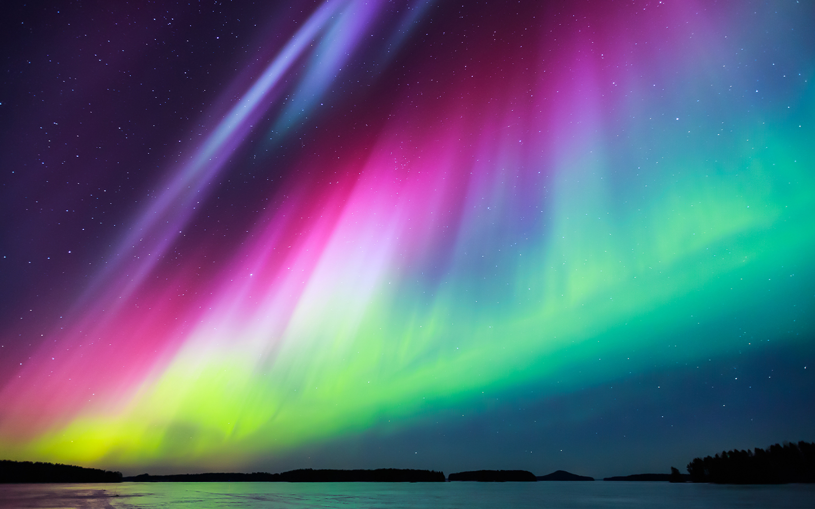 Northern lights display vivid colors over snowy landscape in Norway.