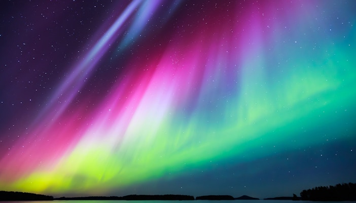 Northern lights display vivid colors over snowy landscape in Norway.