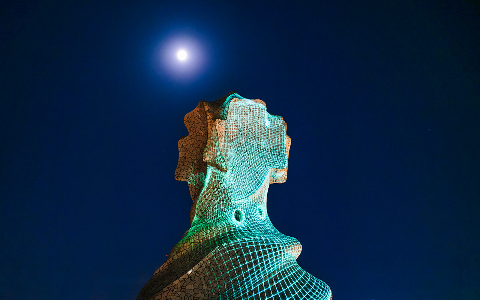 Chimney sculpture at Casa Mila-La Pedrera illuminated at night under a full moon.