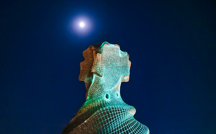 Chimney sculpture at Casa Mila-La Pedrera illuminated at night under a full moon.