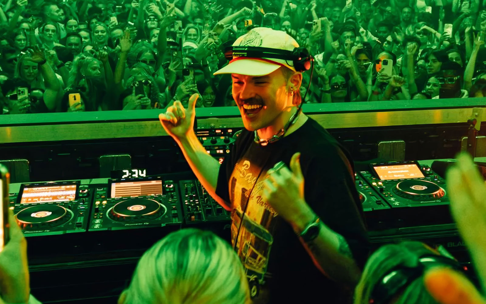 DJ performing at a lively Dom Dolla event in Ibiza with a cheering crowd.