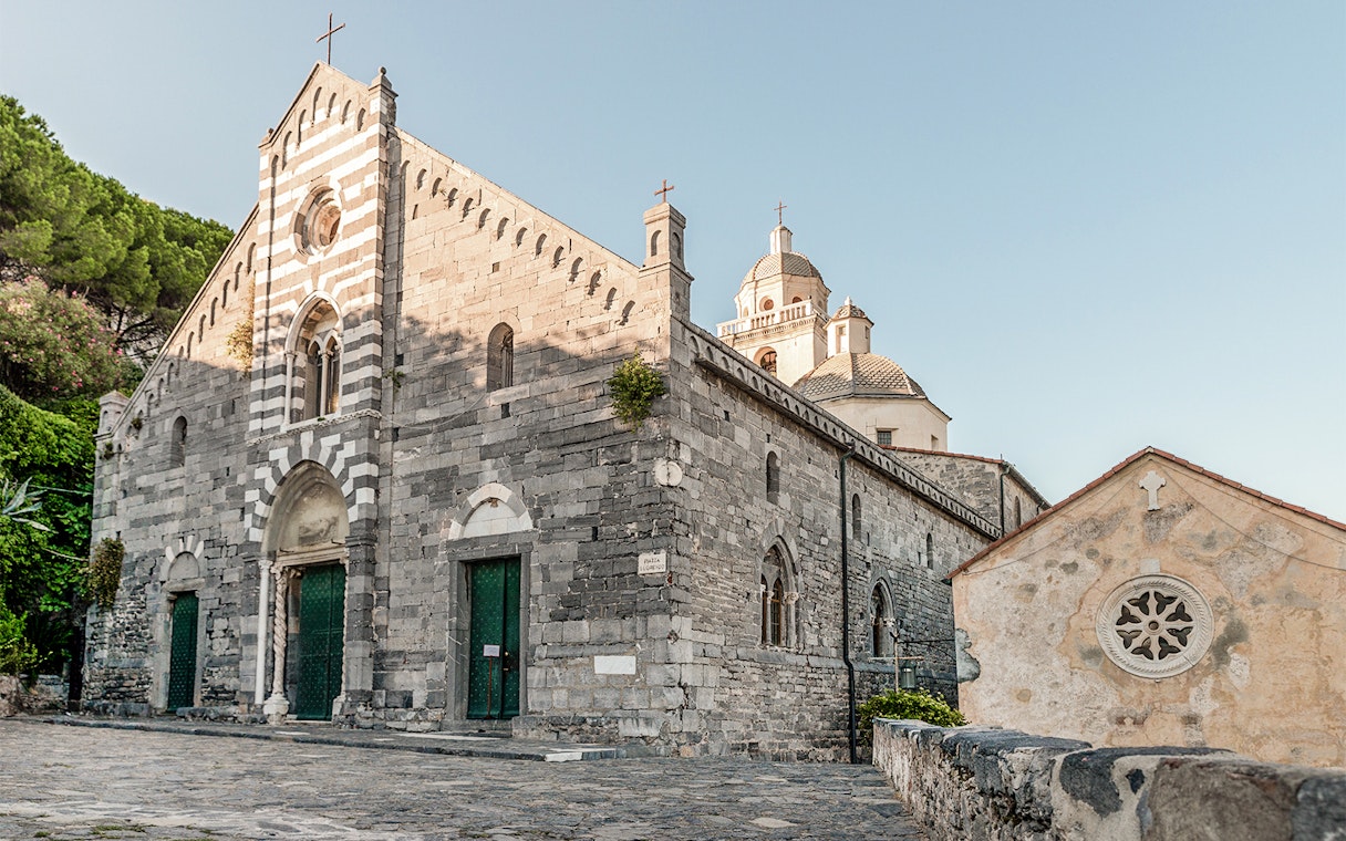 Historic church in Cinque Terre, Italy, with stone facade and green doors.