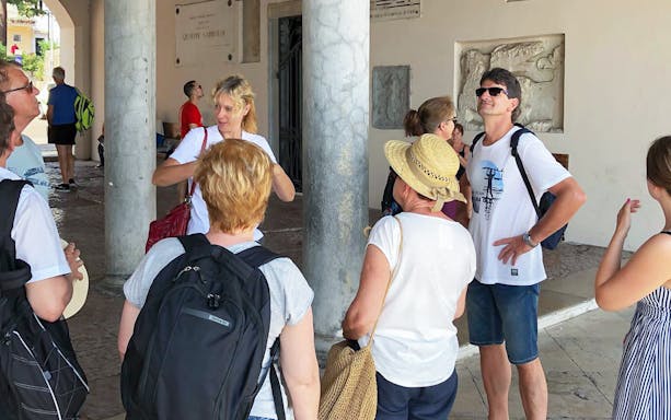 Tour group listening to a guide during a full-day bus and boat tour of Lake Garda.