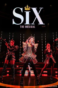 Performers on stage in SIX Broadway musical with vibrant costumes and lighting.