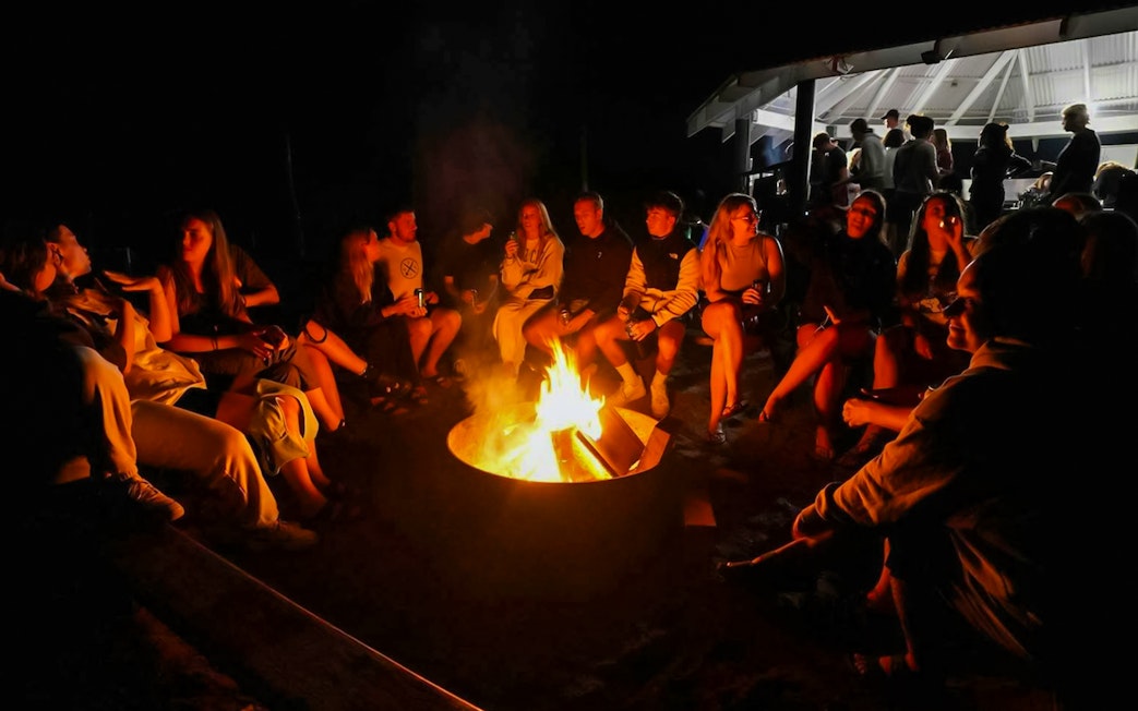 Campfire gathering on Fraser Island, K'gari, with people sitting around the fire.