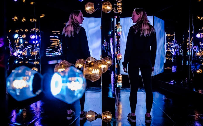 Visitors exploring the colorful light installations at AMAZE Amsterdam.