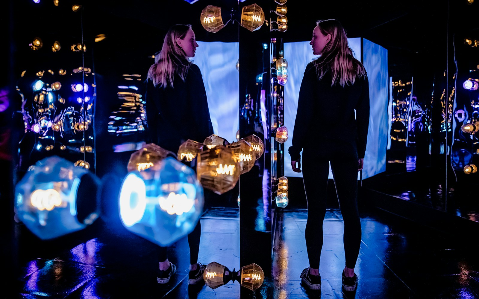 Visitors exploring the colorful light installations at AMAZE Amsterdam.