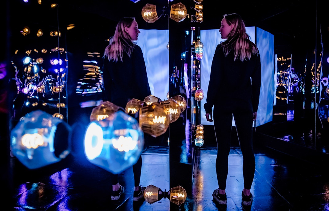 Visitors exploring the colorful light installations at AMAZE Amsterdam.