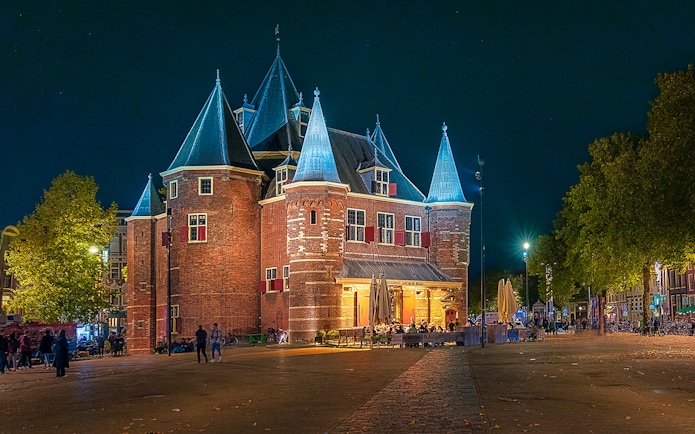 Waag building exterior illuminated at night in Amsterdam.