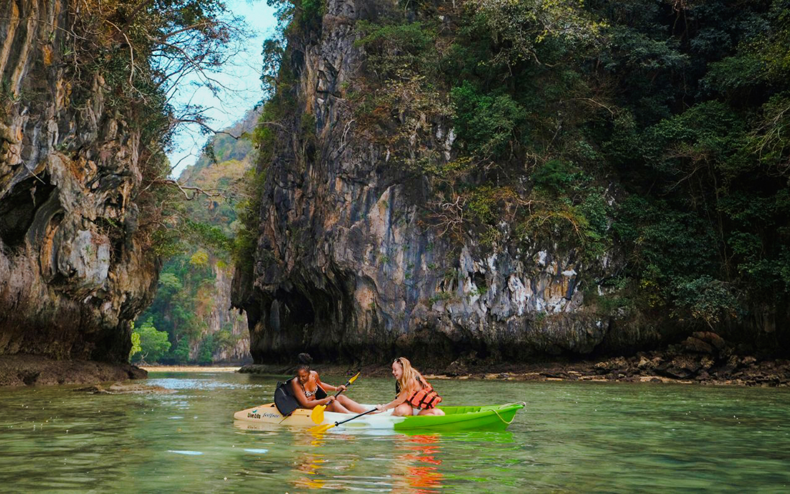 Tourists kayaking through limestone cliffs in Krabi, Thailand.