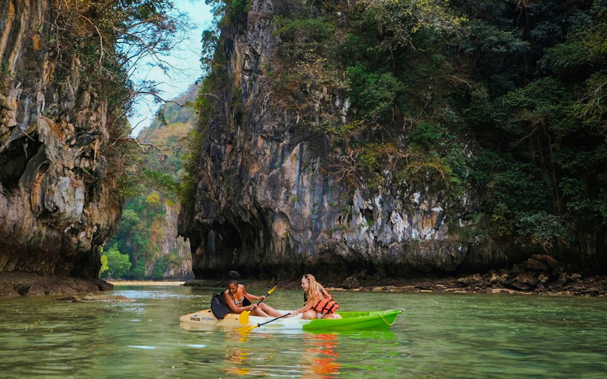 Tourists kayaking through limestone cliffs in Krabi, Thailand.