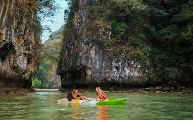 Tourists kayaking through limestone cliffs in Krabi, Thailand.