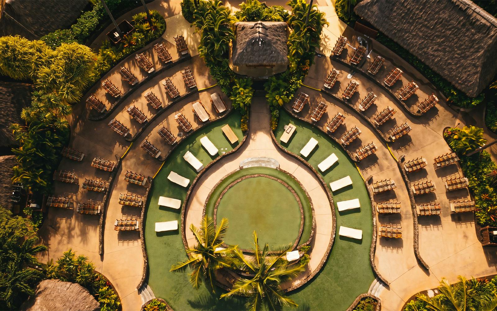 Outdoor seating arrangement at Old Lahaina Luau in Maui, Hawaii, with circular layout and tropical plants.