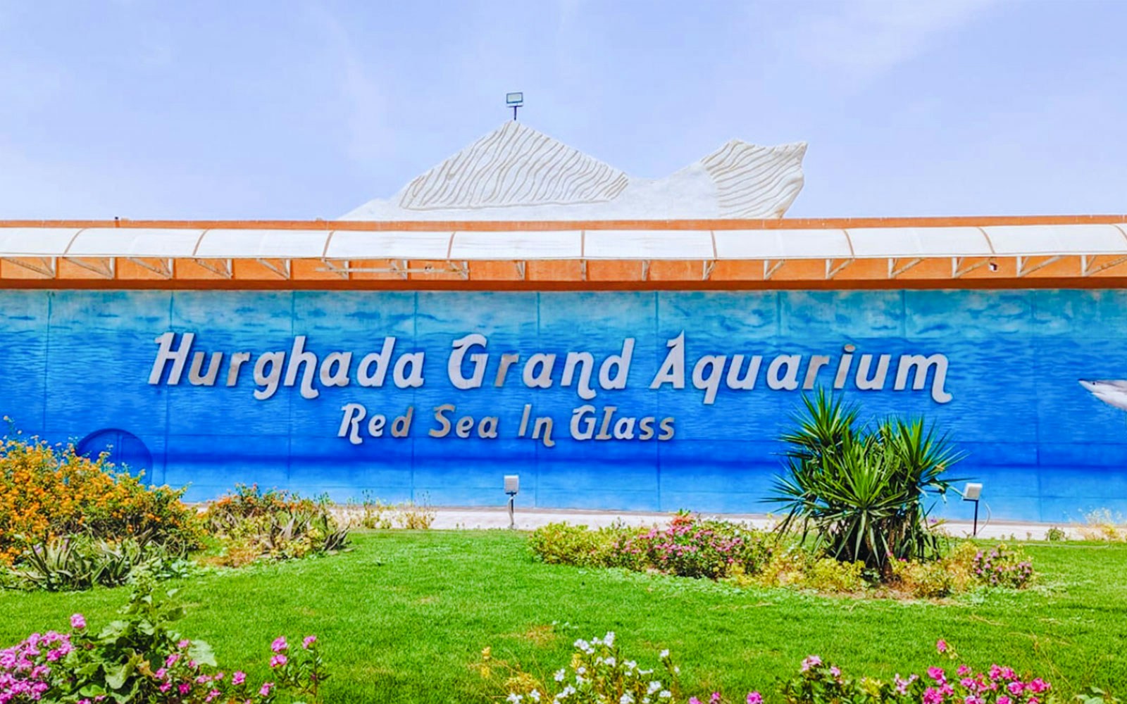 Hurghada Grand Aquarium entrance with garden and signage.