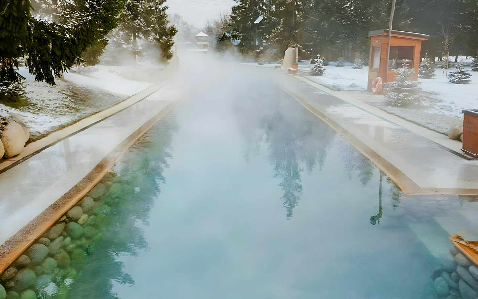 Goracy Potok Thermal Bath with steam rising, surrounded by snow-covered trees near Krakow.