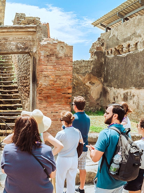 Guide explaining ancient ruins to tourists in Pompeii, near Naples.