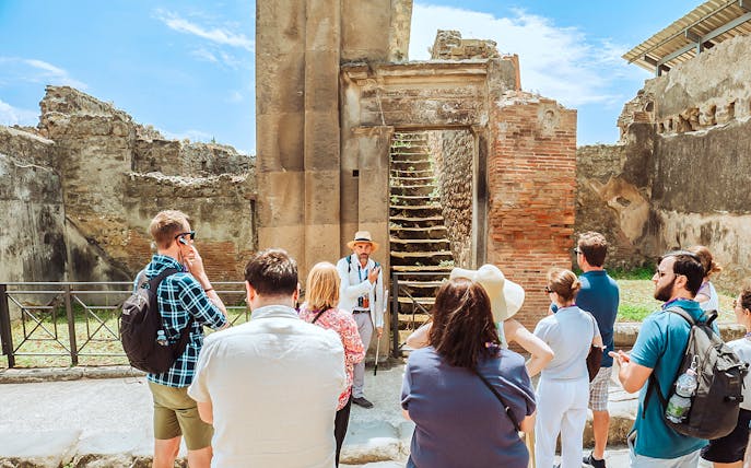 Guide explaining ancient ruins to tourists in Pompeii, near Naples.