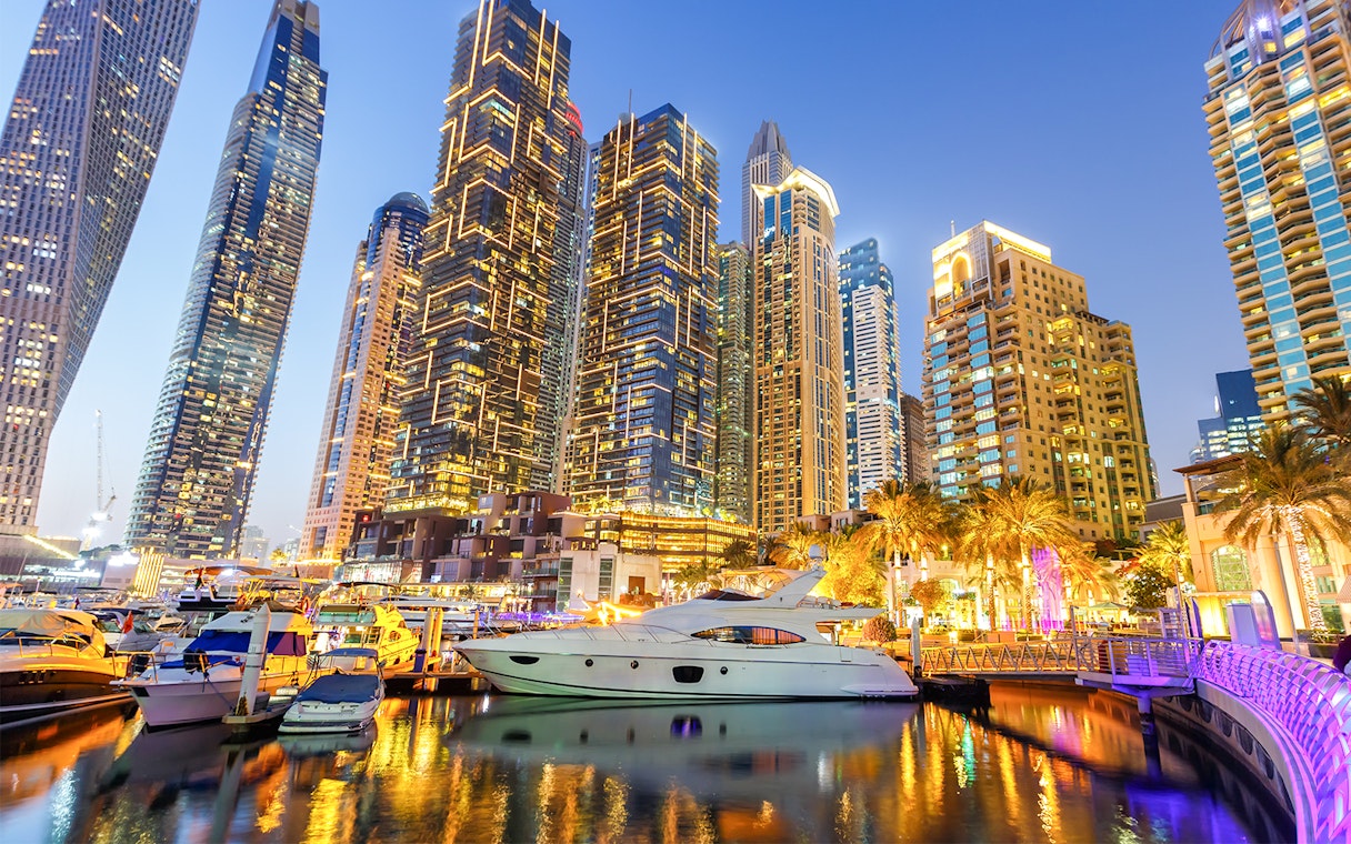 Dubai Marina skyline with yachts in the harbor at dusk.