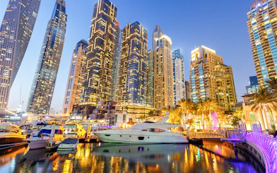 Dubai Marina skyline with yachts in the harbor at dusk.
