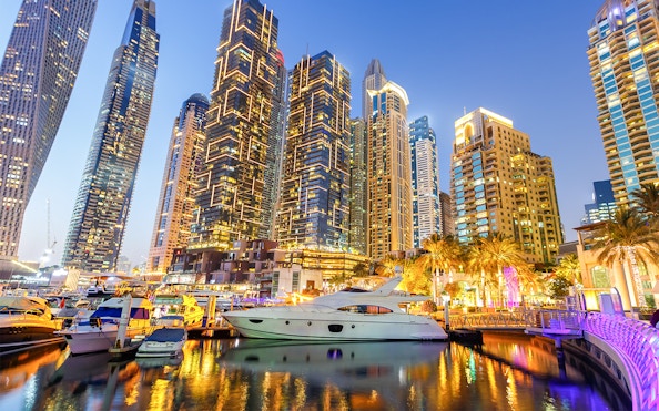Dubai Marina skyline with yachts in the harbor at dusk.
