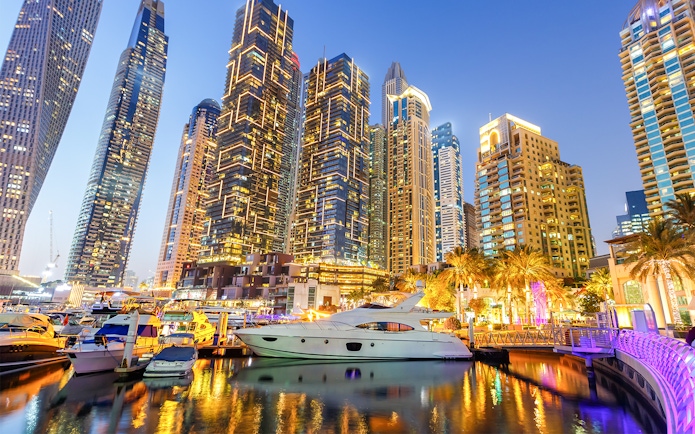 Dubai Marina skyline with yachts in the harbor at dusk.