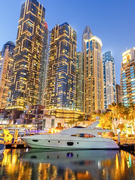 Dubai Marina skyline with yachts in the harbor at dusk.