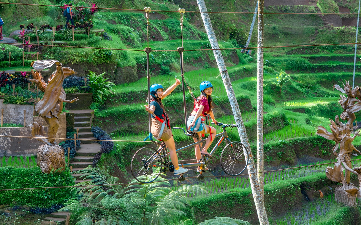 Tourists riding a sky bike over lush terraces at Alas Harum Bali.