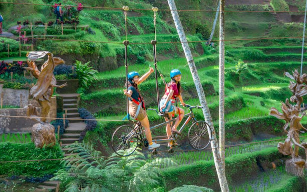 Tourists riding a sky bike over lush terraces at Alas Harum Bali.