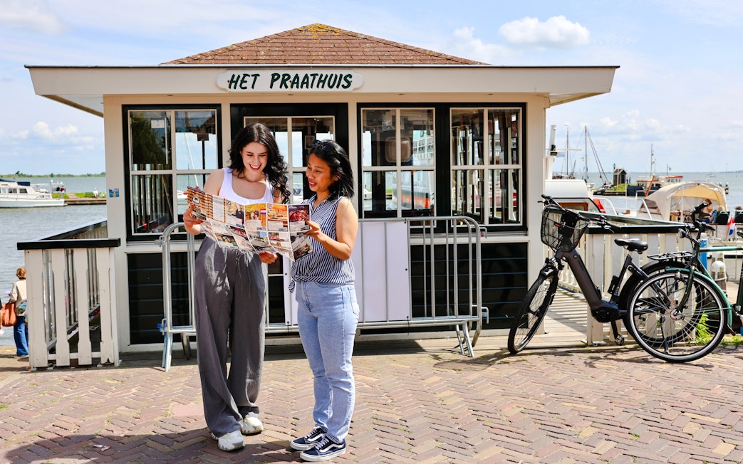 Tourists consulting a map in front of Het Praathuis during a walking tour in Volendam.