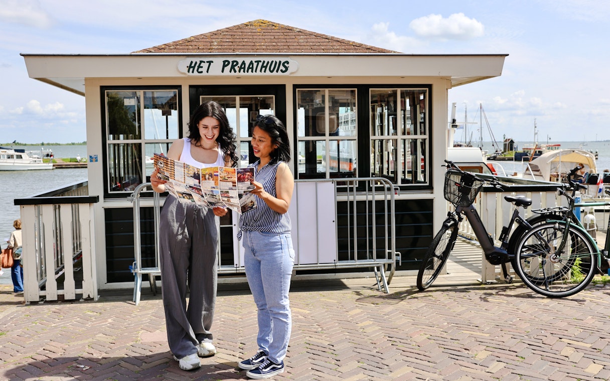 Tourists consulting a map in front of Het Praathuis during a walking tour in Volendam.