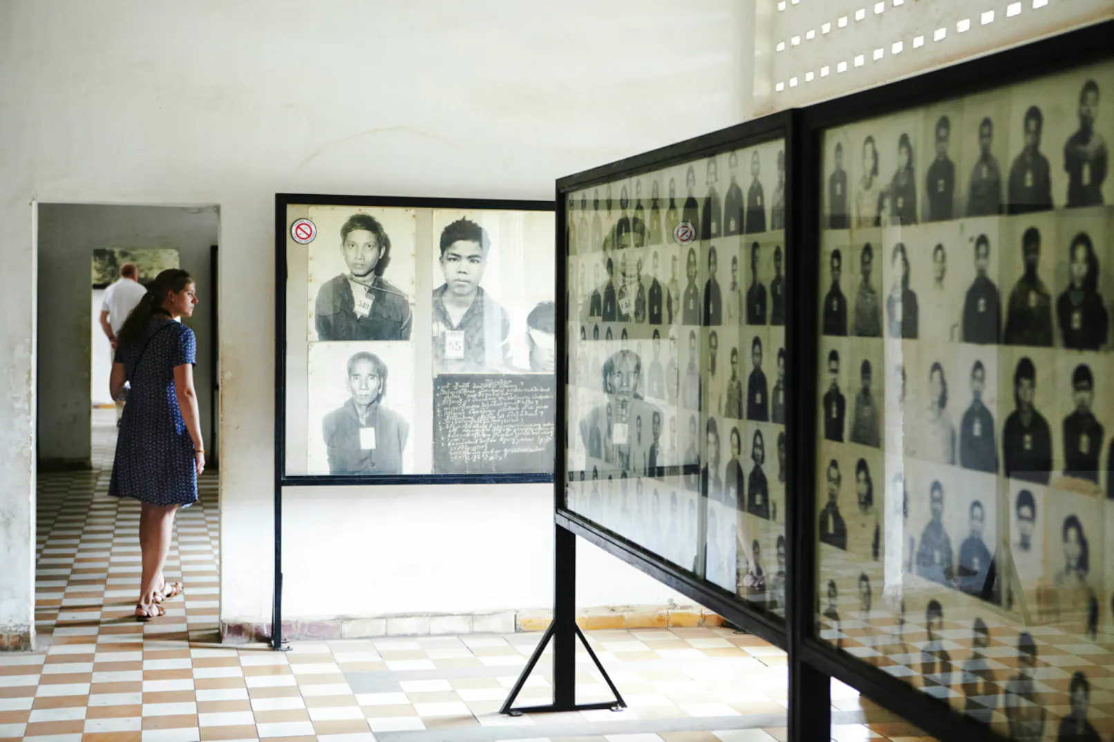 Visitors viewing prisoner photos at Tuol Sleng Genocide Museum, Phnom Penh.