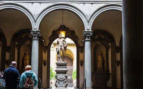 Visitors view a marble statue through arches at Uffizi Gallery, Florence.